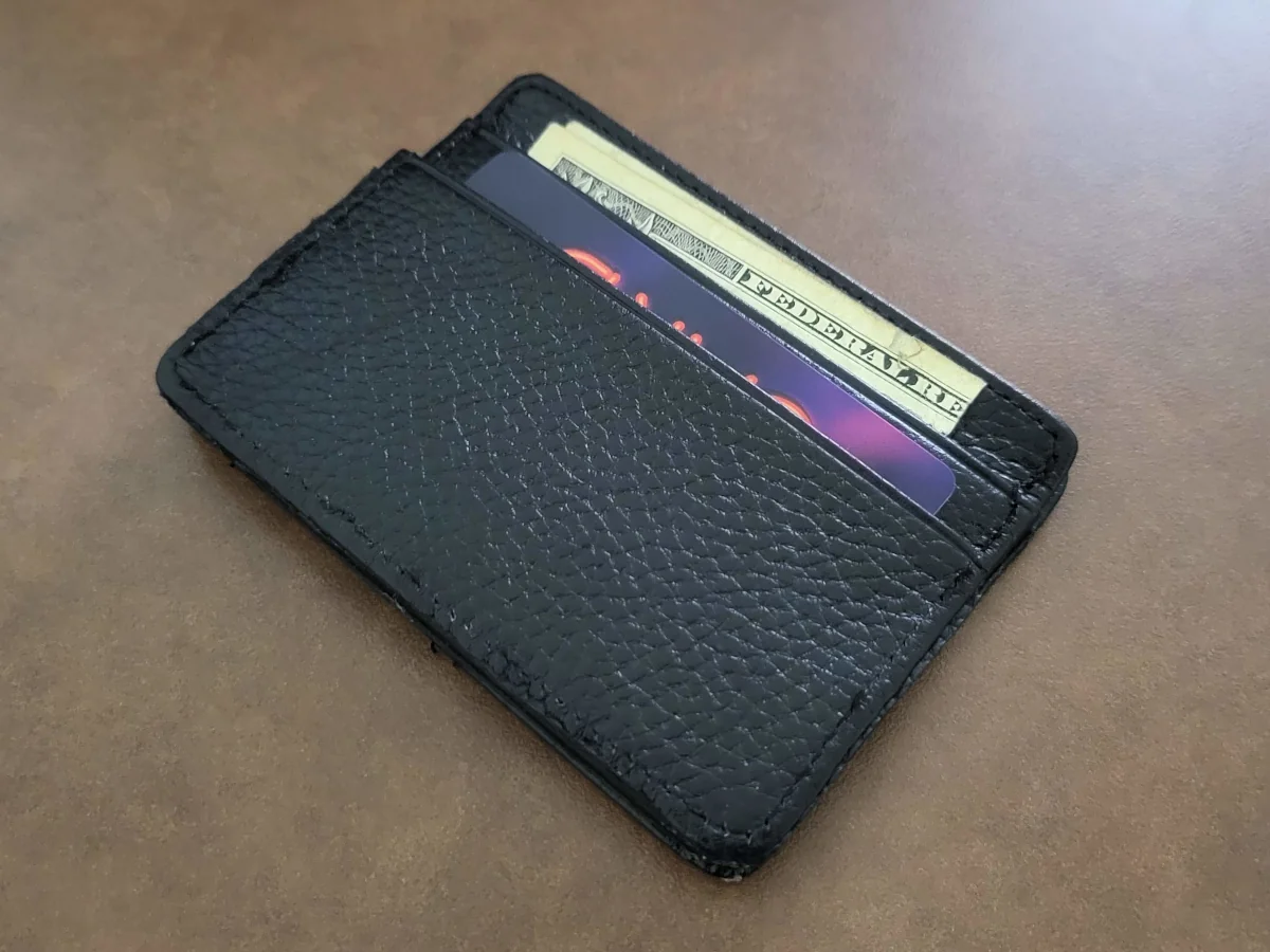 The back of a thin wallet, with a banknote and a credit card sticking out of the pockets.